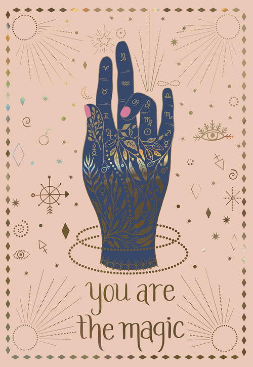 Mystical celestial hand greeting card front with gold zodiac signs, stars, and cosmic details on a pink background, featuring the empowering text 'you are the magic'.