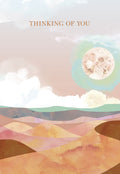 Front of an encouraging watercolor desert greeting card. Features a serene landscape with soft pink, orange, and blue hues, a full moon, and subtle clouds, with the text 'THINKING OF YOU'.