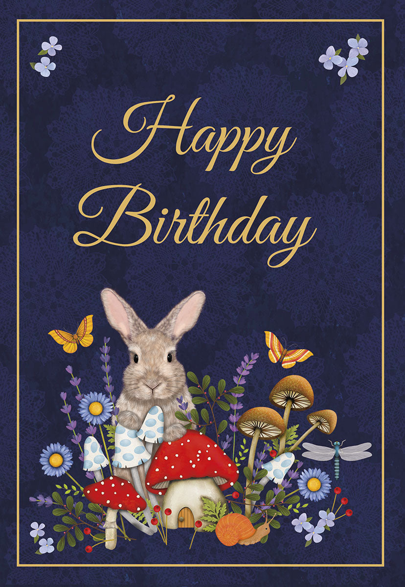 Front of a cute birthday greeting card featuring a whimsical forest scene with a fluffy brown bunny, vibrant red and blue mushrooms, purple and blue wildflowers, and yellow butterflies on a dark navy blue background. Gold script reads 'Happy Birthday'.