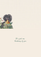 Inside view of a thoughtful friendship card with a heartfelt message 'It's just me. thinking of you.' The bottom left corner shows the illustration of the girl and dog among flowers on a grid-patterned background.