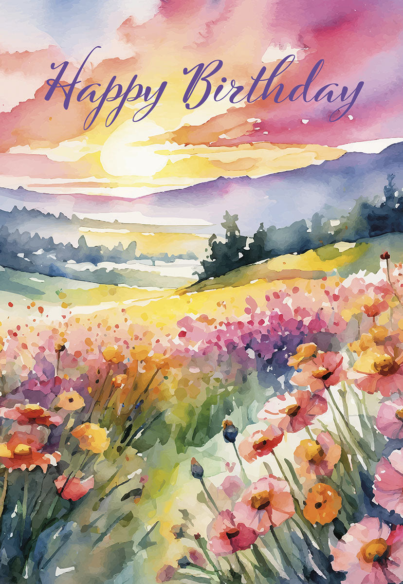 Front of a Happy Birthday greeting card featuring a vibrant watercolor landscape. A field of pink, purple, and yellow wildflowers, possibly poppies, stretches towards rolling hills under a colorful sunrise or sunset sky. The words 'Happy Birthday' are written in elegant script at the top. This artistic card evokes joy and serenity.