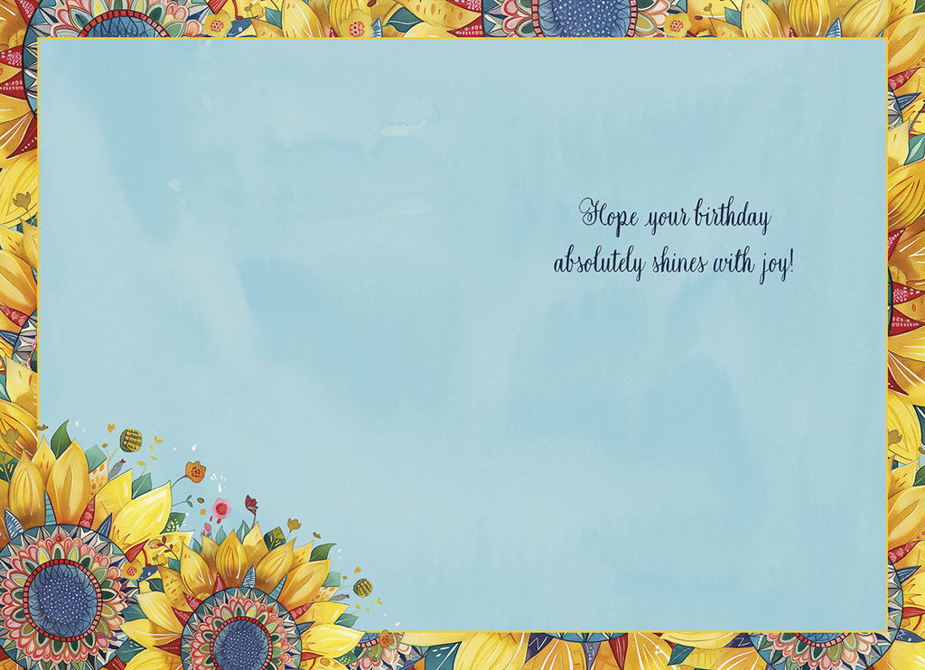 Open lighthearted birthday greeting card interior with a pale blue background, displaying the message 'Hope your birthday absolutely shines with joy!' framed by a decorative border of sunflowers and colorful floral accents.