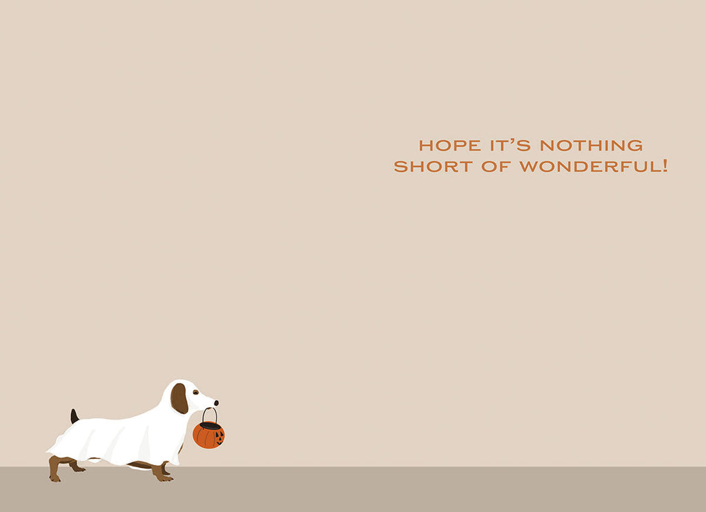Interior of a charming greeting card featuring a small dachshund in a ghost costume with a pumpkin bucket at the bottom, against a light beige background with text 'HOPE IT'S NOTHING SHORT OF WONDERFUL!'. Spooky cute message.