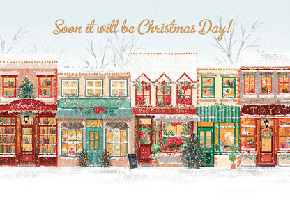 Charming Christmas greeting card featuring a snowy street scene with a row of beautifully decorated shops and the text 'Soon it will be Christmas Day!'