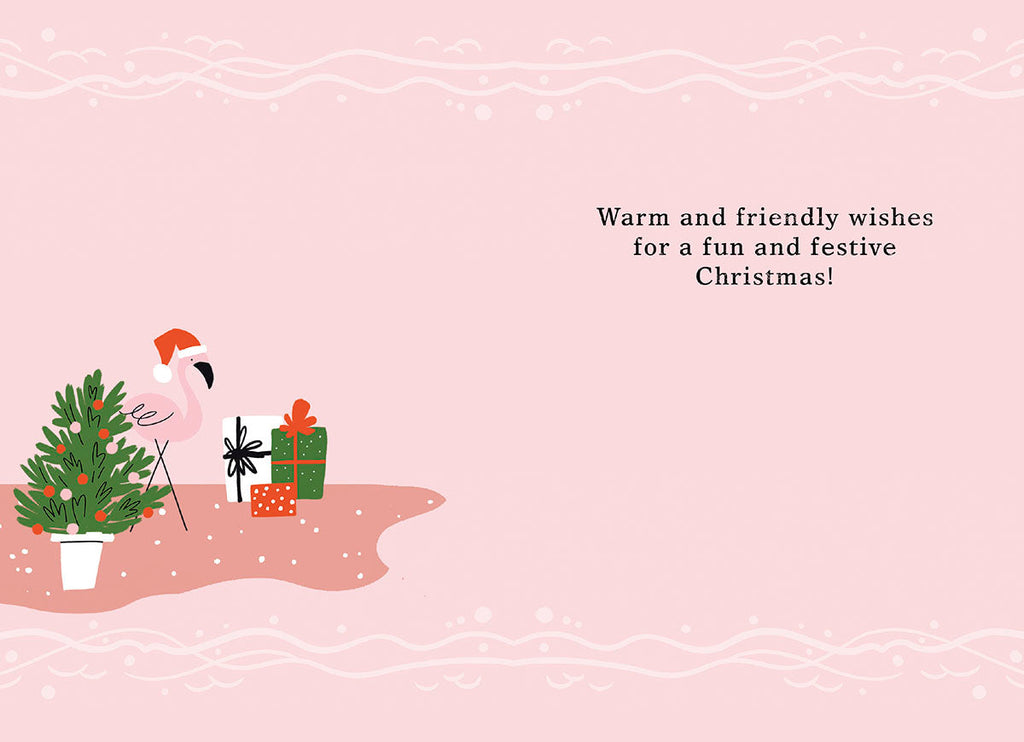 Inside a festive pink holiday greeting card with a whimsical flamingo in a Santa hat, a small decorated Christmas tree, and gifts. The text reads 'Warm and friendly wishes for a fun and festive Christmas!'.