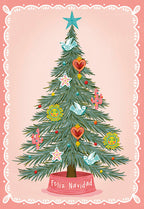 Festive greeting card front featuring a vibrant pine tree adorned with unique Mexican folk art-inspired ornaments like suns, cacti, doves, and sacred hearts, on a pink background with a decorative scalloped border. Text 'Feliz Navidad' at the base.