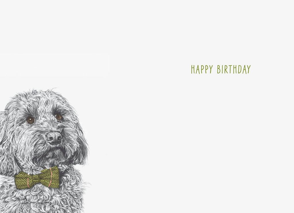Inside view of the birthday greeting card, showing the adorable fluffy gray dog with a green tweed bow tie on the left, and 'HAPPY BIRTHDAY' text centered on the right side of the blank white interior, ready for a personal message.