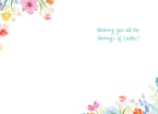 Inside of a white Easter greeting card with subtle watercolor floral corner accents, displaying the light blue handwritten text 'Wishing you all the blessings of Easter!'.