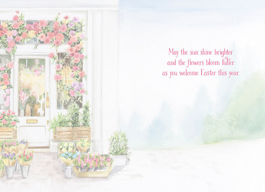 Open greeting card interior with a spring flower shop illustration on the left and a heartfelt message on the right: 'May the sun shine brighter and the flowers bloom fuller as you welcome Easter this year.' Ideal for spring season wishes.
