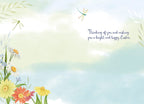 Inside of a lighthearted Easter greeting card with a watercolor sky background, delicate spring flowers, dragonflies, and the message 'Thinking of you and wishing you a bright and happy Easter.'