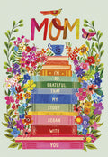 Vibrant Mother's Day greeting card featuring 'MOM' in colorful letters, a stack of storybooks, lush flowers, a bird, and a butterfly. Front message: 'I'M SO GRATEFUL THAT MY STORY BEGAN WITH YOU'.