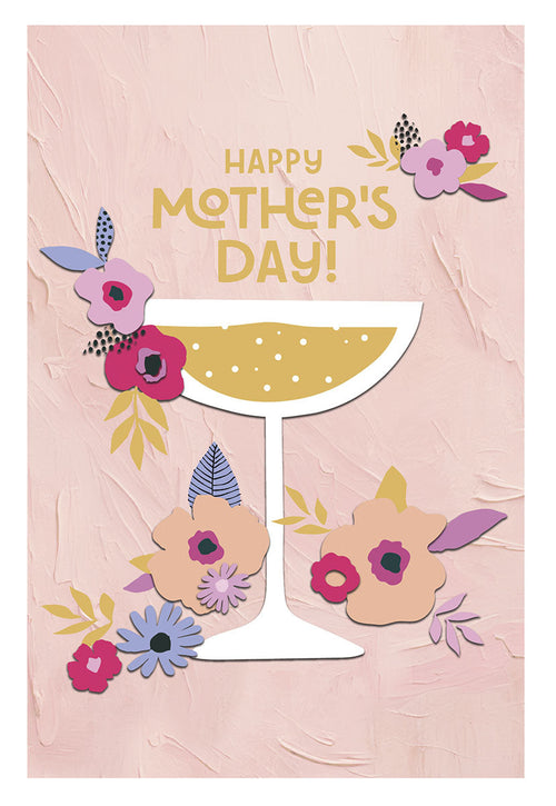 Front of a Mother's Day greeting card featuring 'HAPPY MOTHER'S DAY!' in gold text. A champagne coupe glass with golden bubbly liquid is surrounded by vibrant pink, purple, and blue flowers with green and gold leaves on a textured light pink background.