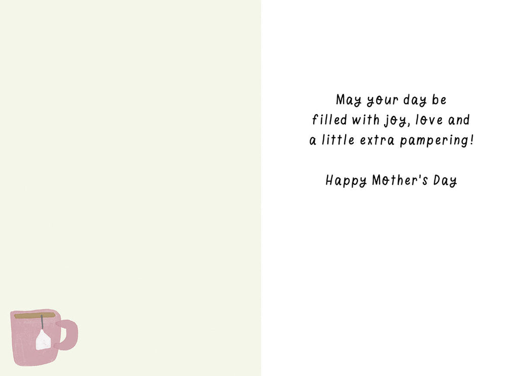 Inside of a thoughtful Mother's Day card, displaying a heartfelt message in script font: 'May your day be filled with joy, love and a little extra pampering! Happy Mother's Day'. A corner of a pink teacup is visible, complementing the card's relaxation theme.