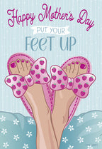 Front of a cheerful Mother's Day greeting card showing feet in pink strawberry slippers relaxing on a light blue pillow, with text 'Happy Mother's Day Put Your Feet Up' on a striped background.