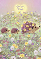 Charming Mother's Day greeting card featuring an illustrated mama hedgehog leading two baby hedgehogs through a vibrant field of yellow and purple wildflowers under a warm sun, with 'Love you, Mom' text at the top, ideal for expressing heartfelt appreciation.