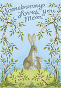 Charming Mother's Day greeting card featuring an adult bunny and a baby bunny on a green hill, framed by blossoming branches, with text 'Somebunny Loves You Mom' on a light blue background. Perfect for moms who love cute animal designs.