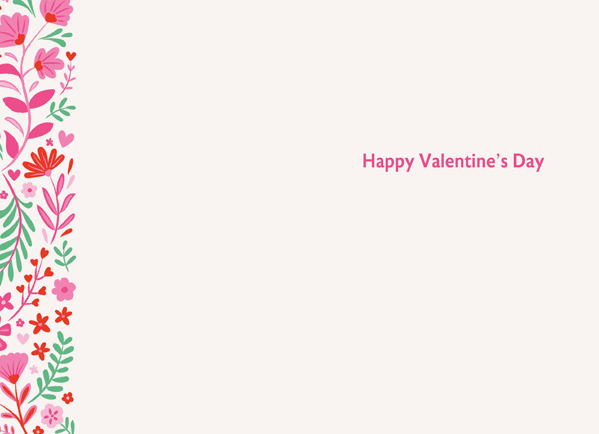Interior view of a heartfelt Valentine's Day card with 'Happy Valentine's Day' in pink script, accented by a floral border on the left with pink and red blossoms and green foliage, offering ample space for a personalized message.