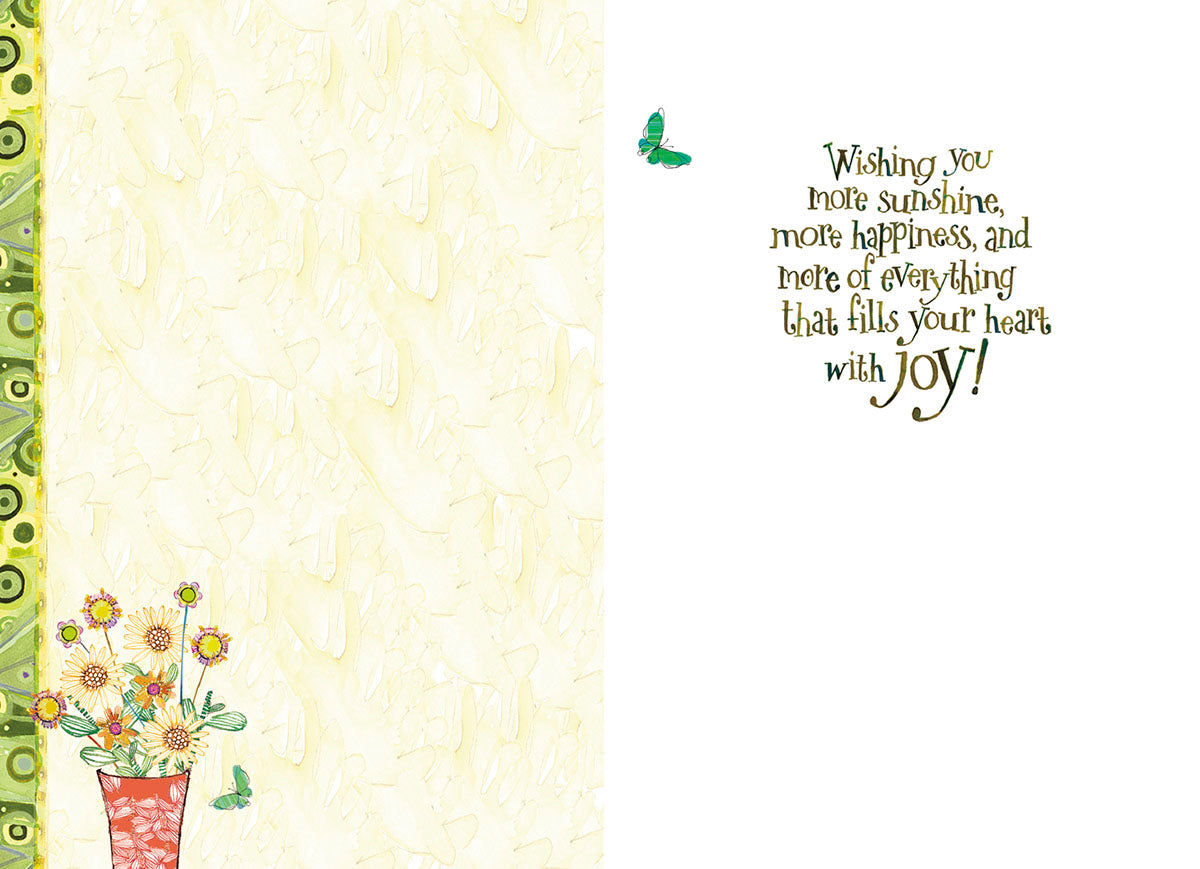 Open view of a 'Happy Birthday' card interior, showing a gentle cream-colored background, a small floral bouquet in a red pot, and the heartfelt message: 'Wishing you more sunshine, more happiness, and more of everything that fills your heart with joy!'