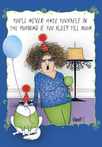 Funny birthday greeting card featuring a cartoon woman with messy hair, sunglasses, and a party hat, holding a green drink next to a birthday cake. A cool cat in a party hat and sunglasses sits beside her. A blue balloon floats nearby. Text reads: "YOU'LL NEVER HATE YOURSELF IN THE MORNING IF YOU SLEEP TILL NOON."