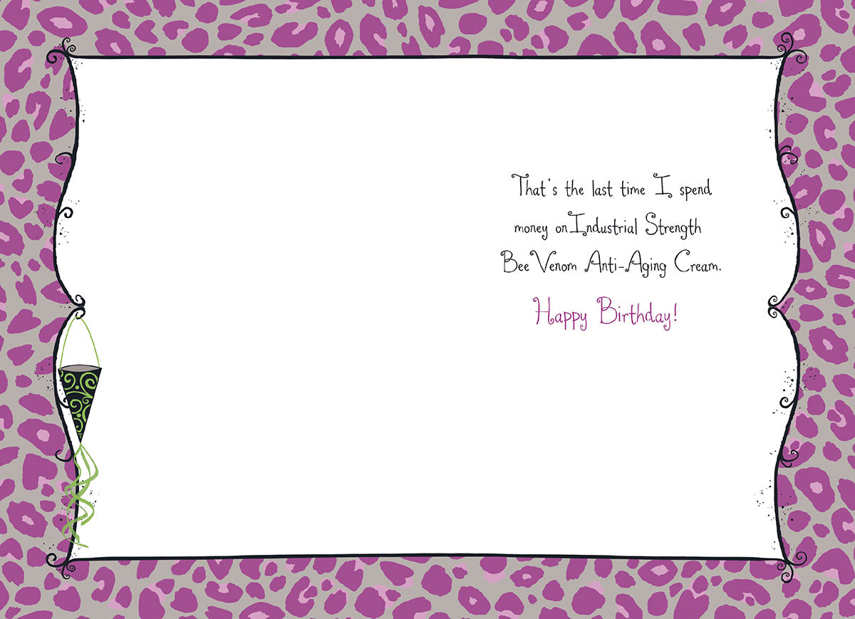 Inside of a humorous birthday greeting card, revealing the witty punchline 'That's the last time I spend money on Industrial Strength Bee Venom Anti-Aging Cream. Happy Birthday!' against a playful purple leopard print border.
