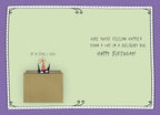 The inside of a funny birthday greeting card. The left side shows a small black cat in a party hat peeking from a box with the text "IF IT FITS, I SITS." The right side has handwritten-style text that reads "HOPE YOU'RE FEELING HAPPIER THAN A CAT IN A DELIVERY BOX. HAPPY BIRTHDAY!" The card has a light green background with a dotted purple border.