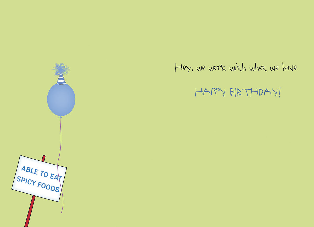 Inside of a humorous birthday card for him, showing a blue balloon with a sign 'ABLE TO EAT SPICY FOODS' and the text 'Hey, we work with what we have. HAPPY BIRTHDAY!' on a light green background.