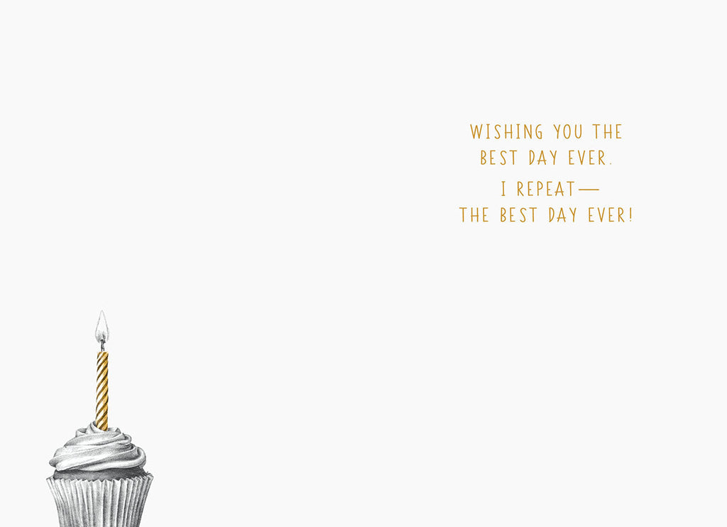 Inside of a humorous greeting card showing a small, detailed drawing of a cupcake with a single gold candle, and text wishing 'WISHING YOU THE BEST DAY EVER. I REPEAT— THE BEST DAY EVER!'. The design is clean and lighthearted.