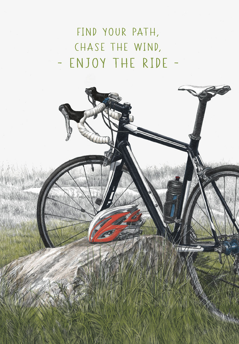 Illustrated greeting card featuring a black road bicycle leaning against a rock in a grassy field, with a red helmet beside it. Text reads: 'FIND YOUR PATH, CHASE THE WIND, - ENJOY THE RIDE -'. Ideal for him, a friend, or any cycling enthusiast.
