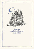 Front of an encouragement greeting card for her, featuring a hand-drawn illustration of a golden retriever dog and a tabby cat sitting together under a crescent moon and stars, with the comforting text 'some days might feel heavier than others' in blue script. The card has a soft cream background and a subtle blue border, conveying a heartfelt, supportive, and peaceful sentiment for a friend.
