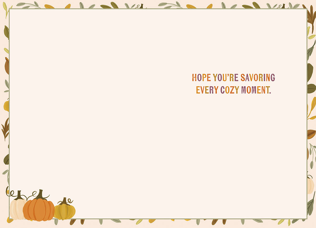 Inside view of a cozy autumn greeting card with the message 'HOPE YOU'RE SAVORING EVERY COZY MOMENT.' printed in orange and purple, framed by an elegant border of green leaves, yellow foliage, and small pumpkins.