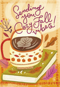 Cozy fall greeting card front featuring a warm mug of hot cocoa with leaf latte art, resting on an autumn-themed book, surrounded by fall leaves and the text 'Sending you Cozy Fall Vibes!'. Perfect for friends celebrating harvest season or leading up to a festive October.