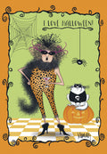 Sassy woman in leopard print jumpsuit, black boa, and big, wild hair holding a martini glass. She stands next to a black cat with a skull shirt, perched on a grinning jack-o'-lantern. A spiderweb and spider hang in the green background, with the text 'I LOVE HALLOWEEN!' The card has an orange decorative border.