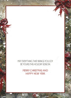 The inside of a holiday greeting card features a decorative border of snowy fir branches and red bows. The printed message reads: 'MAY EVERYTHING THAT BRINGS YOU JOY BE YOURS THIS HOLIDAY SEASON. MERRY CHRISTMAS AND HAPPY NEW YEAR'.