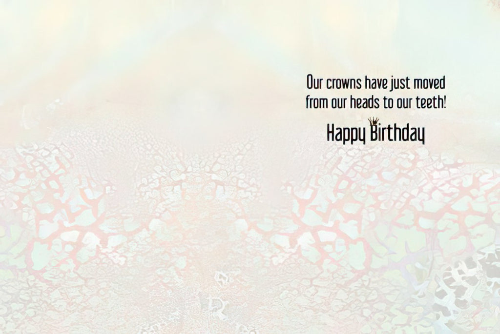 Inside of a funny greeting card with text 'Our crowns have just moved from our heads to our teeth! Happy Birthday' on a light, textured background, revealing the humorous message.