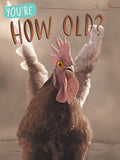 Humorous greeting card featuring a surprised brown rooster with pink comb and yellow eyes, text reads 'You're How Old?' on a rustic background. Funny chicken age milestone card.