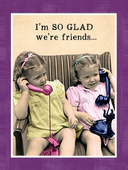Two smiling young girls talking on vintage pink and black rotary phones. Front of a funny friendship greeting card.
