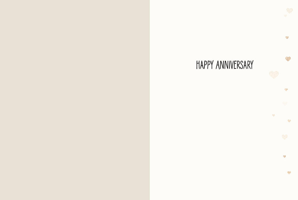 Inside view of a romantic anniversary card with 'HAPPY ANNIVERSARY' printed on the right panel, adorned with delicate gold hearts, and a blank left panel for a personalized message.