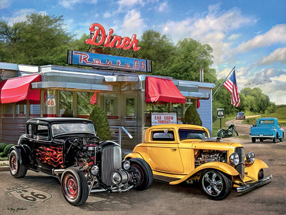 Two classic hot rods, a black one with flames and a yellow one, parked in front of a retro Route 66 diner under a cloudy sky.