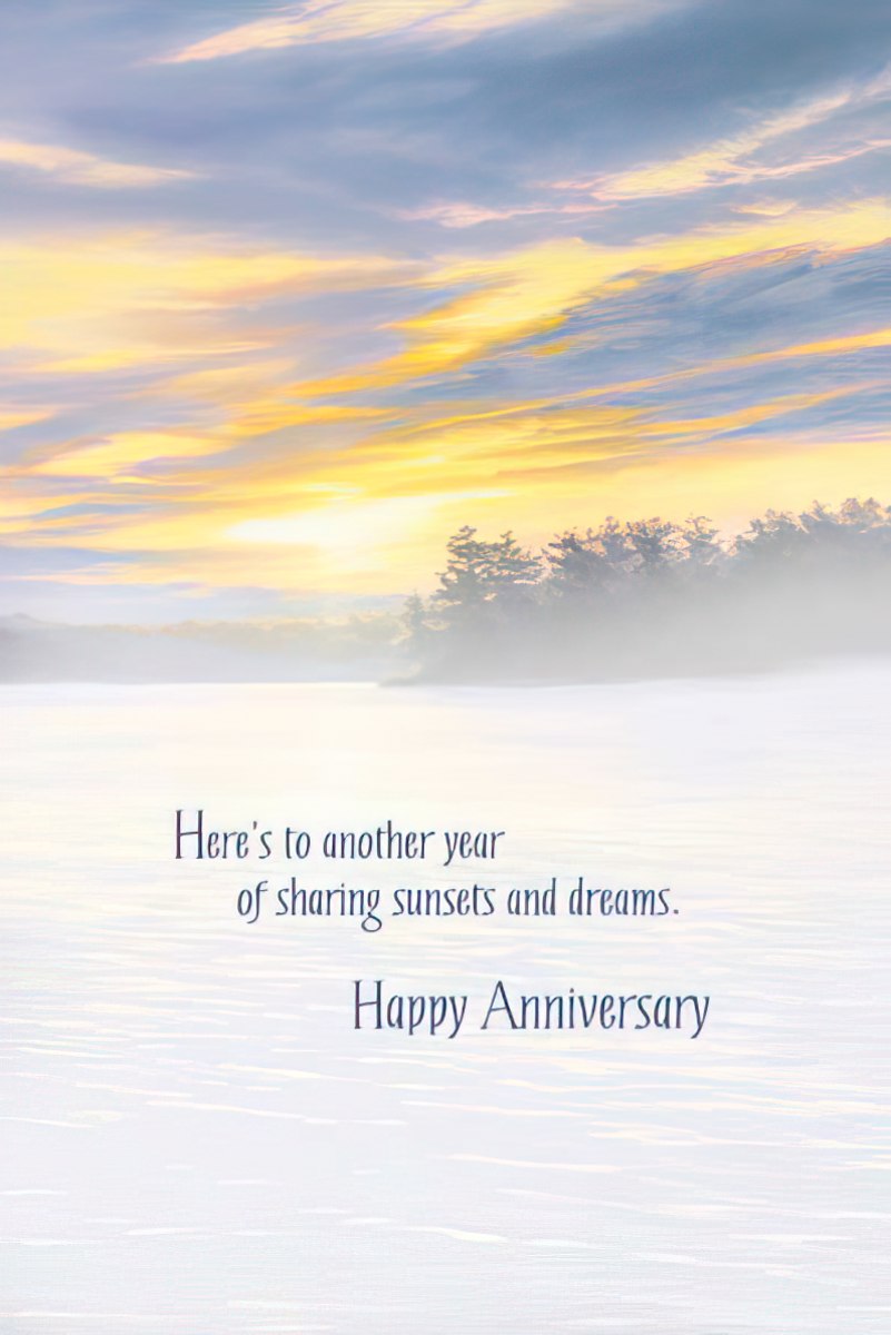 Inside of a greeting card featuring a soft misty lake and sunset background, with text: 'Here's to another year of sharing sunsets and dreams. Happy Anniversary.'