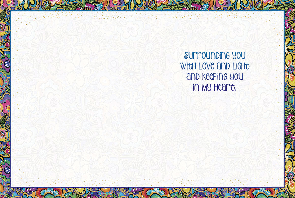 Inside of a white encouragement card with a colorful floral border, text 'Surrounding you with love and light and keeping you in my heart'.
