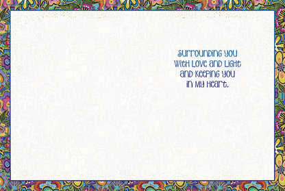 Inside of a white encouragement card with a colorful floral border, text 'Surrounding you with love and light and keeping you in my heart'.