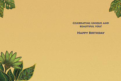 Inside of a light tan birthday card with green tropical leaves in corners. Text: 'CELEBRATING UNIQUE AND BEAUTIFUL YOU! HAPPY BIRTHDAY'.