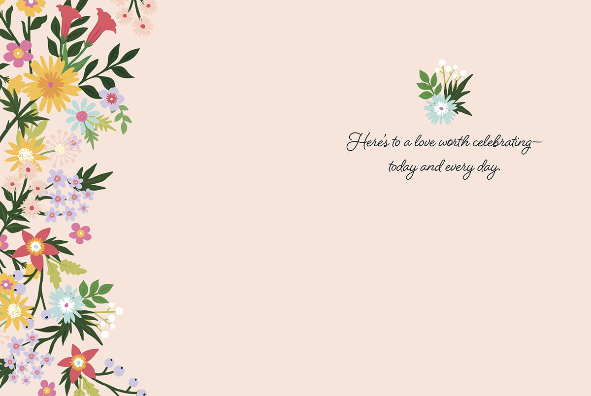 Inside of an anniversary card with a soft pink background, a delicate floral border, and the heartfelt message about lasting love.