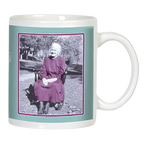 White ceramic mug featuring a vintage-style black and white photo of a smiling elderly woman in a dress sitting outdoors, framed by a teal border.