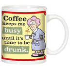 Front view of a white ceramic coffee mug featuring a funny cartoon of an older woman in a bathrobe with pink hair, holding a steaming coffee cup. Text reads: 'Coffee keeps me busy until it's time to be drunk.' on a yellow and green background.