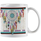 White ceramic mug featuring a vibrant Native American inspired dreamcatcher design with colorful feathers and an artisan turquoise center, handle visible.