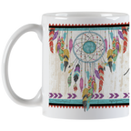 White ceramic mug displaying a beautiful dreamcatcher graphic with multi-colored feathers and a central turquoise stone, beside part of the inspiring 'new dreams are born' quote.