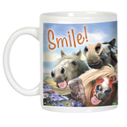 White ceramic mug featuring a wraparound funny horse design. Three cartoon horses are depicted with amusing faces, including one with buck teeth and a wide smile, and two with tongues playfully sticking out. The word "Smile!" is written in orange script above them, against a bright sky and green field background.