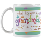 Angled view of a white ceramic handle mug featuring the full colorful 'What happens at grandma's stays at grandma's' quote, surrounded by playful handprints and paint splatters, a unique gift for grandmas.