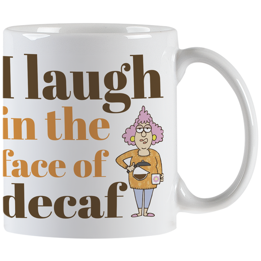 Close-up front view of a white ceramic coffee mug with the slogan 'I laugh in the face of decaf' in brown and orange text, featuring a sassy cartoon woman holding a coffee pot.